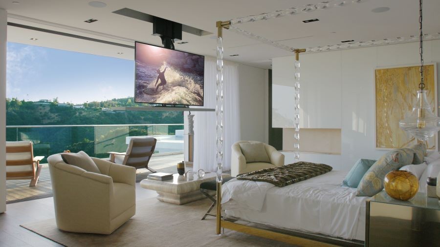 A bedroom with large picture windows and a TV that descends from a lift in the ceiling.