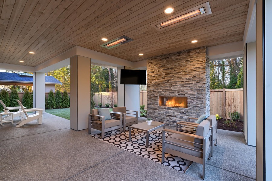 An outdoor living space with a fireplace, TV, and architectural lighting fixtures.
